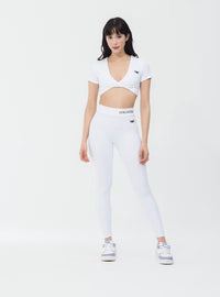 Girl Standing in White Short Sleeve Workout Crop Top with Twist Design UK